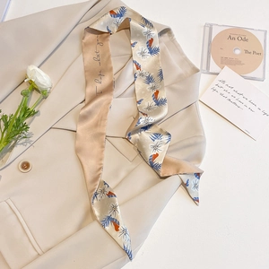 Close-up of a floral beige twilly scarf draped on a blazer with delicate floral patterns
