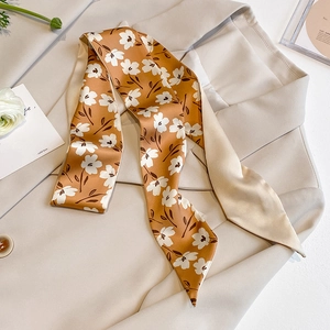 Detail of a ginger silk scarf with white floral patterns on a beige blazer jacket
