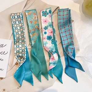 Nahaufnahme verschiedener Seidenschals mit Blumendruck auf einem beigefarbenen Blazer