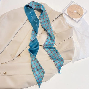 Detail eines Seidenschals mit blauem geometrischem Muster auf einem cremefarbenen Blazer
