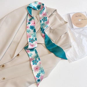Detail eines geblümten Satin-Schals auf einem beigen Blazer mit kunstvollen Requisiten