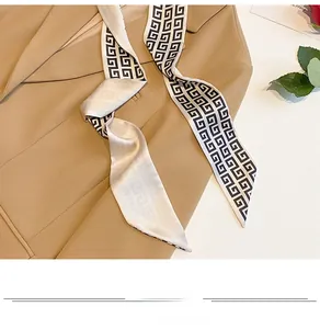 Detail of geometric pattern silk scarf styled with a khaki blazer for elegant look