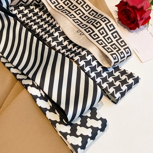 Detailed view of assorted black and white patterned narrow silk scarves on khaki blazer