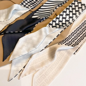 Macro detail of various patterned silk twilly scarves arranged in a fan shape layout