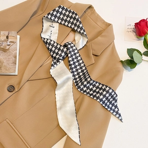 Narrow black and white star pattern silk scarf tied on a khaki blazer collar