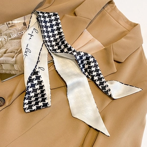 Detail of silk-like twilly scarf with houndstooth and star patterns on a khaki blazer