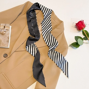Detail of a thin silk scarf with black and white stripes on a beige blazer jacket