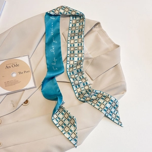 Zweiseitiger schmaler Seidenschal mit geometrischem Muster und Spruch auf beigem Blazer