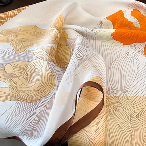 Detailed close-up of cream floral silk scarf with vibrant orange lily prints
