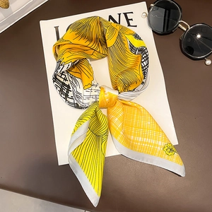 Floral print silk-like scarf in bright yellow and black hand-drawn lines displayed on a stand