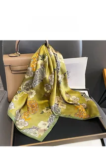 Détail d'un foulard en soie verte avec imprimé floral vintage sur un sac en cuir