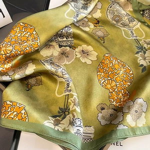 Détail d'un foulard en soie de luxe avec motifs floraux verts et texture satinée