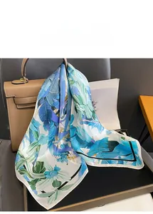 Détail d'un carré de soie à imprimé floral tropical drapé sur un sac à main en cuir