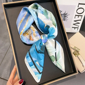 Carré de soie bleu élégant à motif floral présenté sur un plateau noir mat