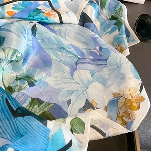 Vue détaillée de la texture du foulard en soie avec motifs de peinture florale bleue