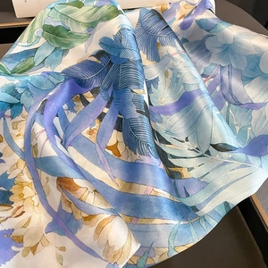 Détail macro d'imprimés tropicaux sur foulard en soie brillant aux tons bleu et jaune