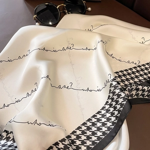 Detailaufnahme eines Seidenschals mit Hahnentritt-Muster und elegantem Schriftzug-Print