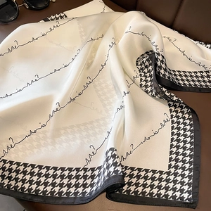 Detail eines Seidensatin-Halstuchs mit Hahnentrittmuster und modischem Schriftzug