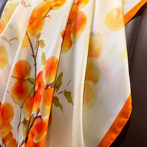 Macro shot of faux silk scarf with orange persimmon print and bright contrast border