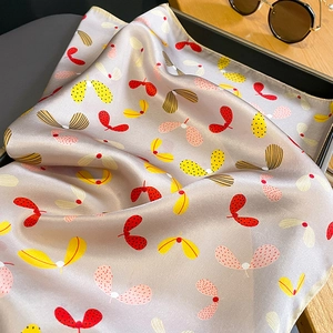 Detailed view of paisley silk scarf with satin luster on a wooden desk with sunglasses
