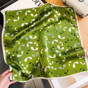 Detailed texture of green silk square scarf with floral paisley patterns and white border