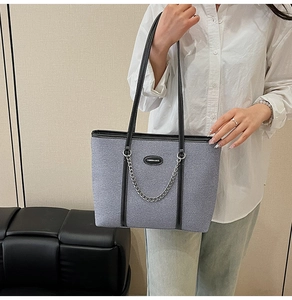 Dettaglio della borsa tote in denim azzurro con finiture in pelle nera e catena argento