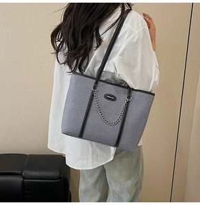 Borsa tote grigia intrecciata con catena argento e manici neri indossata da una modella