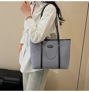 Dettaglio della borsa tote in denim grigio con finiture in pelle nera e catena trendy