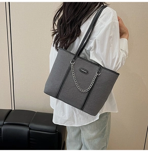 Dettaglio della borsa tote grigia con trama intrecciata, catena argento e logo moda