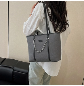 Dettaglio della borsa tote in denim grigio scuro con catena argento e spalline in pelle