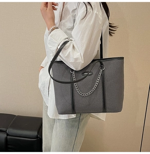 Dettaglio della borsa tote in denim grigio con finiture in pelle nera e catena