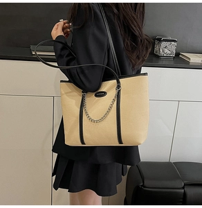 Dettaglio della borsa tote beige in tela con finiture in pelle nera e catena argento