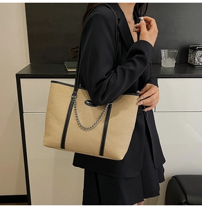 Dettaglio della borsa tote intrecciata kaki con finiture in pelle nera e catena argento