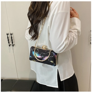 Detalle de bolso de noche con plumas coloridas y asa de anillo dorada