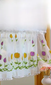 Detail of tulip embroidery and white pom-pom trim on sheer lace kitchen cafe curtains