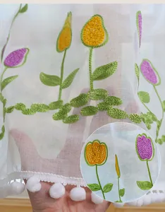 Detail of tulip embroidery and pom-pom trim on translucent polyester cafe curtain