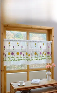 Detail of tulip embroidery on white lace cafe curtain with pompom fringe trim