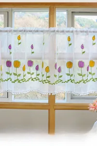 Close-up of tulip embroidery and white pom-pom fringe on translucent cafe curtain