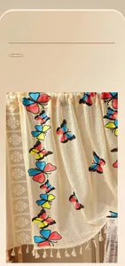 Detail of floral butterfly embroidery on beige lace curtain with cotton fringe accents