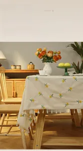 Detail of off-white woven tablecloth with yellow floral embroidery and white tassels