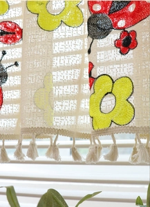 Detailed view of floral embroidery and ladybug motifs on lace coffee curtain with tassels