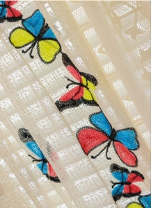 Close-up of beige mesh lace curtain with vibrant butterfly embroidery and tassel detail