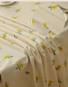 Detail showing cream embroidered tablecloth with yellow floral patterns and lace edge