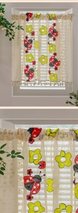 Detail of lace cafe curtain with embroidered ladybugs and floral tassels