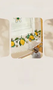 Detail of floral lace cafe curtain featuring yellow lemon embroidery and wavy edges