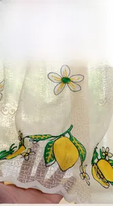 Detail showing embroidered lemon pattern on semi-transparent beige curtain fabric