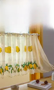 Detail of embroidered lemon patterns and scalloped edges on a beige cafe lace curtain