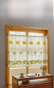 Detail of white cafe curtain with embroidered lemons and elegant scalloped lace border