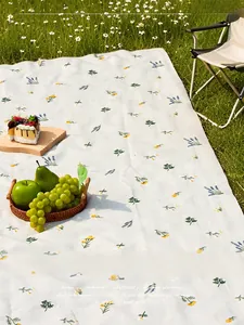 Detail of embroidered sunflower picnic mat on green grass with scenic outdoor decor