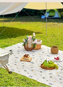 Close-up of thick floral picnic blanket with yellow daisies on outdoor grass